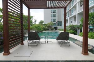 Si Maha Phot304花园酒店的一个带两把椅子和一张桌子的庭院,毗邻一个游泳池