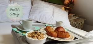 阿伯丁Heather Cottage Aberdeen的床上的托盘,包括羊角面包和咖啡