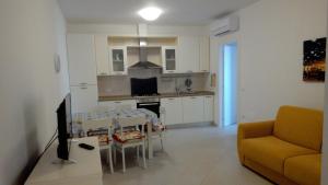 托尔托雷托Verde Mare "Appartamenti per Vacanze"的厨房以及带桌子和沙发的客厅。