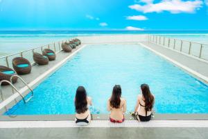 岘港Yarra Ocean Suites Danang的三个穿着泳衣的女人坐在游泳池里