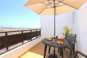 普拉亚布兰卡Villa Emma Playa Blanca的阳台上配有带雨伞的小桌子