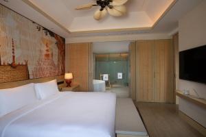 Menghai西双版纳悦椿温泉度假酒店的卧室配有白色的床和吊扇