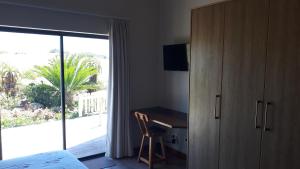 乔治Oubaai Ocean View Private Self catering rooms Herolds Bay的一间卧室配有一张床、一张书桌和一个窗户。