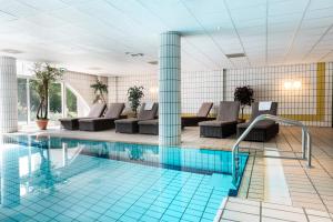 西泰尔斯海灵WestCord Hotel Schylge的游泳池位于酒店客房内,配有椅子和桌子