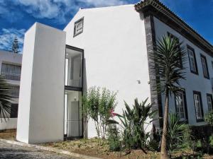 蓬塔德尔加达Azores Youth Hostels - Sao Miguel的一座白色的建筑,有门和一些植物