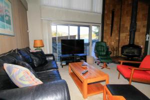 马姆莫斯湖Sierra Park Villas #24的客厅配有黑色真皮沙发和电视
