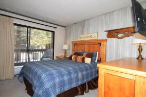 马姆莫斯湖Sierra Park Villas #93的一间卧室配有一张带蓝色毯子的床和窗户。