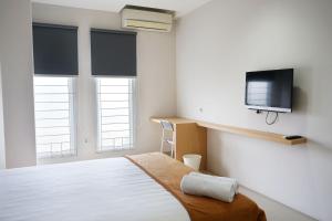 雅加达UROOMS Senayan的卧室配有一张床,墙上配有电视。