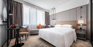 广州广州华厦大酒店的酒店客房设有一张白色大床和一张桌子。