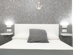 福尔内利斯Apartament Fora Port的卧室配有白色的床和墙上的锚