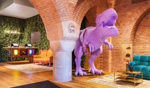 阿姆斯特丹Bunk Hotel Amsterdam的一个带椅子的房间中紫色的恐龙雕像