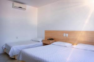 泰谢拉迪弗雷塔斯Pioneiro Hotel的配有白色床单的酒店客房内的两张床