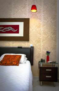 泰谢拉迪弗雷塔斯Pioneiro Hotel的一间卧室配有一张床和一个床头柜,并备有广告