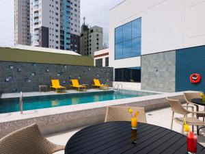 伊达贾伊Novotel Itajai的一个带桌椅的庭院和一个游泳池