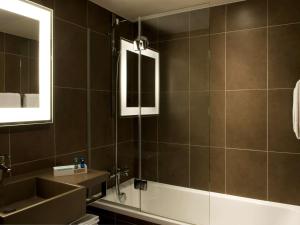 莱斯坎诺沃特里尔机场酒店的一间带水槽、浴缸和镜子的浴室