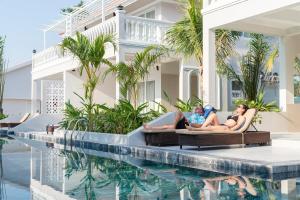 富国水星富国岛别墅度假村 的两名妇女躺在游泳池旁边的躺椅上