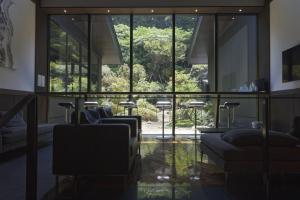 箱根仙石原芒草原一之汤日式旅馆的客厅设有玻璃墙、椅子和窗户