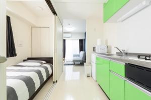 冈山Cocostay KO Residence Sennichimae#603ココステイ ケーオーレジデンス センニチマエ#603的一间卧室配有一张床,厨房配有绿色橱柜