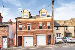 牛津3 Bedroom Townhouse near South Park Oxford - close to city centre !的红砖建筑,有两个白色车库门