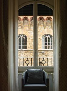 佛罗伦萨安缇卡托瑞迪维亚托尔纳布奥尼酒店的砖楼前带椅子的窗户