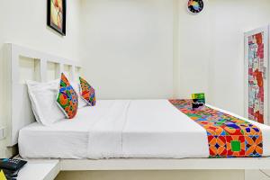 钦奈FabHotel Colors Service Apartment的卧室配有白色的床和色彩缤纷的枕头