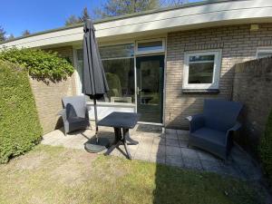 奥特罗Bungalows Hoefbos的庭院配有两把椅子、一张桌子和一把遮阳伞