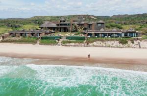 拉巴拉德纳圣米格尔科诺阿专属海滩Spa度假酒店的两个人站在房子前面的海滩上