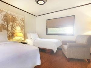龙目岛库塔龙目岛诺富特度假别墅据点的酒店客房,配有两张床和椅子