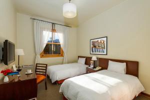 塔尔马LP Los Portales Hotel Tarma的酒店客房设有两张床和电视。