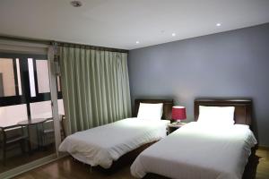 大田Residence Hotel Lamia的一间卧室设有两张床、一张桌子和一个窗口