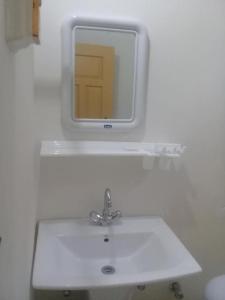 Benazir Hotel Kalash的白色浴室水槽和墙上的镜子