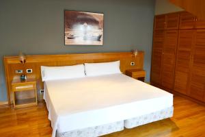 费罗尔Hotel Alda El Suizo的卧室配有一张白色大床和木制床头板
