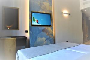 米兰莫肯巴国王酒店的一间卧室配有一张床,墙上设有一台平面电视