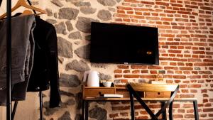 欧里亚克Hôtel Zadig的砖墙上的电视,配有桌子和椅子