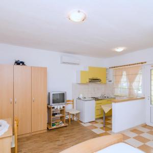 萨普伦纳拉Apartments Skurla的一间厨房,配有黄色和白色的橱柜和一台电视机
