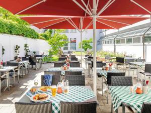 慕尼黑慕尼黑城北宜必思酒店的一个带桌椅和遮阳伞的庭院