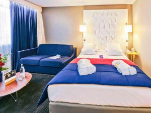 雷恩雷恩中心国会大厦美居酒店的酒店客房设有一张大床和一张蓝色的沙发。