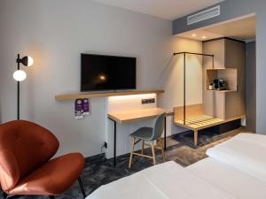 慕尼黑慕尼黑斯彻瓦宾美居酒店的酒店客房配有一张床和一张书桌及一台电视