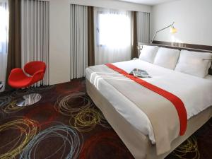 尼奥尔尼奥尔马莱波特温美居酒店的酒店客房设有一张大床和一张红色椅子。
