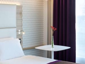 朗吉斯巴黎奥利朗吉斯机场美居酒店的一间房间,配有一张床和一张桌子,上面有花瓶