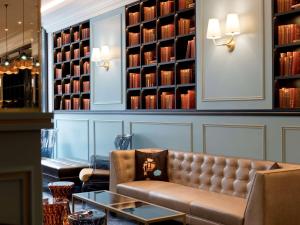 日内瓦Hotel Rotary Geneva - MGallery的配有书籍的房间的皮沙发