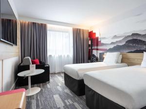 安锡Novotel Annecy Centre的酒店客房设有两张床和一张桌子。