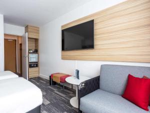 安锡Novotel Annecy Centre的酒店客房配有床、沙发和电视。
