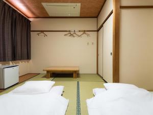 TakamiyaTabist Hotel Kurama Hikone的一间设有三张白色床和一张桌子的房间