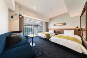 川崎HOTEL METROPOLITAN KAWASAKI的酒店客房,设有两张床和一张沙发