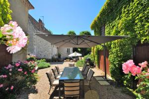 Le FleixManoir du Bois Mignon Luxury Home - Dordogne的庭院配有桌椅和遮阳伞。