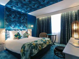 梅里尼亚克波尔多机场美居酒店的一间卧室配有一张特大号床和蓝色天花板