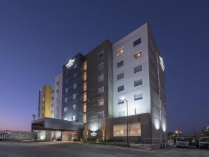 伊拉普阿托Microtel Inn & Suites by Wyndham Irapuato的一座大型建筑,前面设有停车场