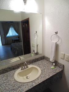 古斯曼城Hotel Hacienda的浴室的柜台设有水槽和镜子
