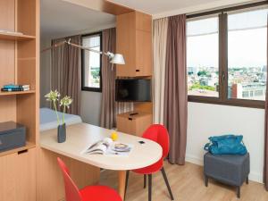 图卢兹Aparthotel Adagio Toulouse Centre Ramblas的酒店客房配有桌子和红色椅子